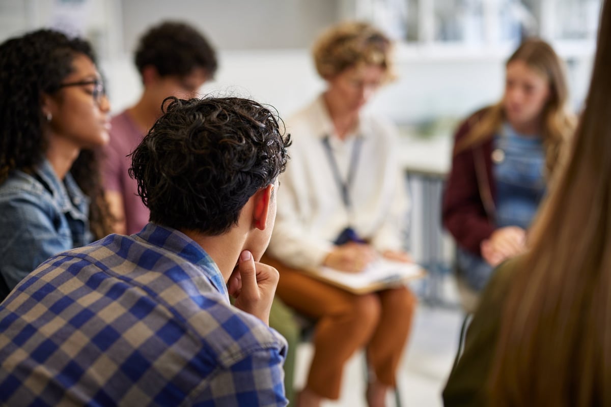 A multiethnic group sitting in a circle with a counselor during a supportive group discussion